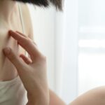 Riflesso di una persona allo specchio, evidenziando la pelle e i segni di salute o disagio.