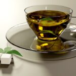 Tazza di tè verde fumante con foglie fresche, simbolo di un metabolismo attivo.