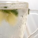 Tazza di acqua calda con limone su un tavolo, simbolo di salute e perdita di peso al mattino.