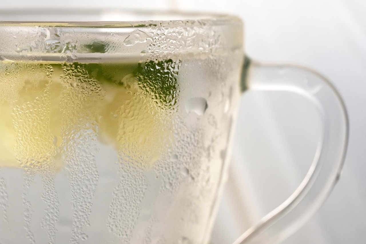 Tazza di acqua calda con limone su un tavolo, simbolo di salute e perdita di peso al mattino.