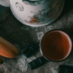 Tazza di tè verde fumante con foglie di tè e limone, simbolo di un metabolismo attivo e sano.