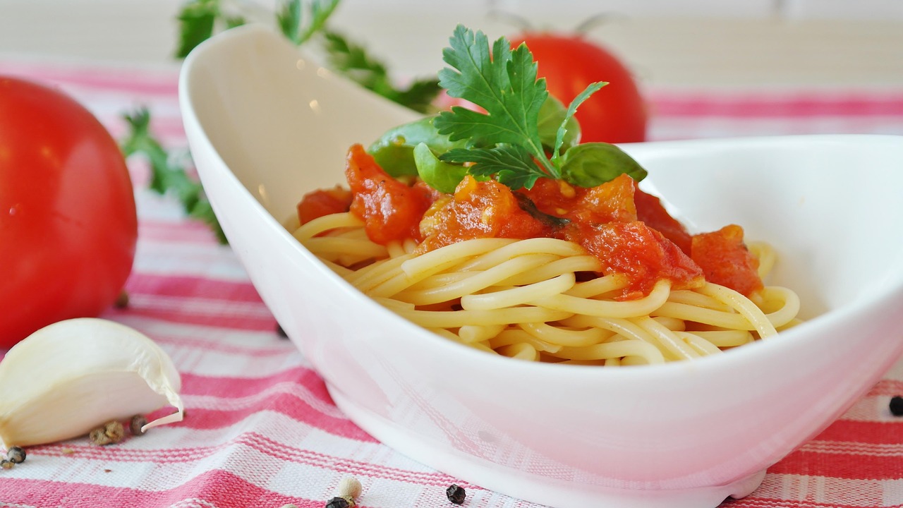 Pasta al pomodoro servita in un piatto, con ingredienti freschi sullo sfondo.