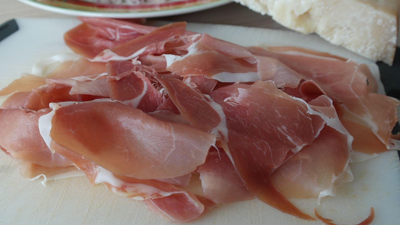 Immagine di una fetta di prosciutto crudo con un avviso su potenziali rischi per la salute.